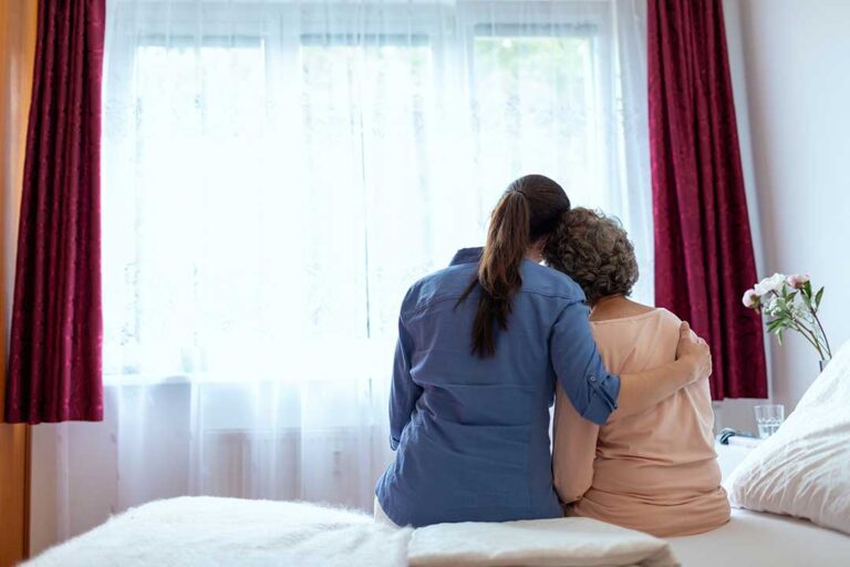 Older adult and family member reviewing care questions with a staff member in a bright assisted living common room.