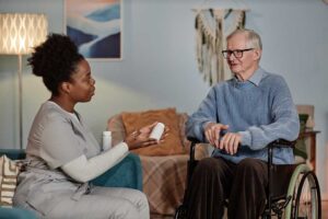 An older adult reviews household bills with a family member at a kitchen table